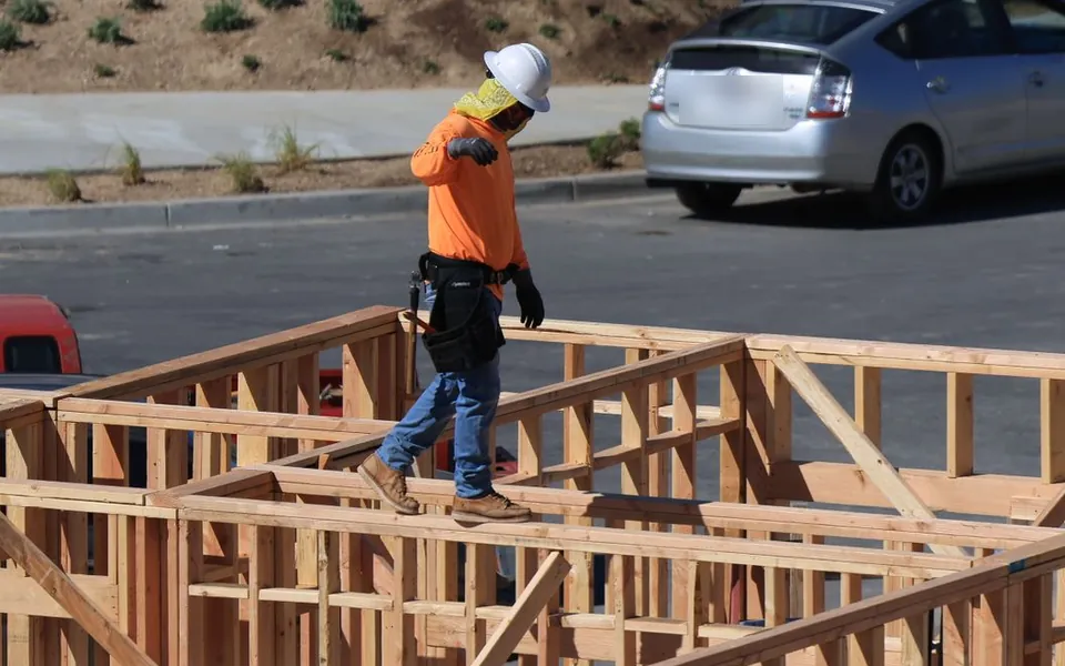 A framer walking a timber-frame wall
