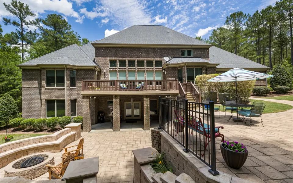 A brick home's backyard with a stone patio and fire pit