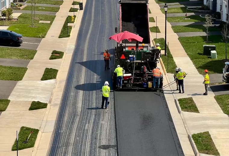A paving crew and machine laying asphalt, seen from above